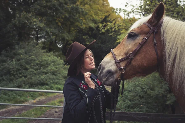 Cowgirl petting näsan av hennes häst. — Stockfoto