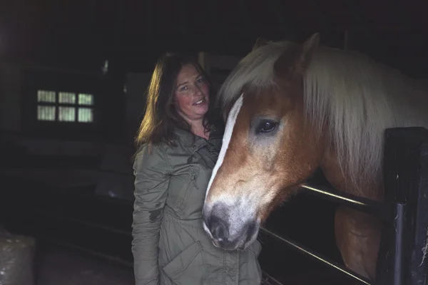 Leende kvinna som står vid häst — Stockfoto