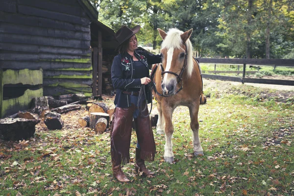 Cowgirl permanent met paard — Stockfoto