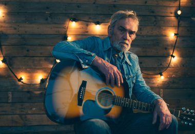 Sandalyede oturan sakallı üst düzey gitarist