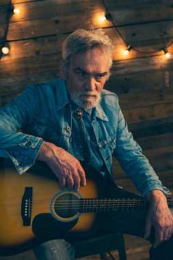 Sandalyede oturan sakallı üst düzey gitarist