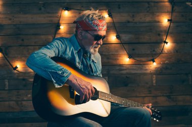 Sandalyede oturan sakallı üst düzey gitarist