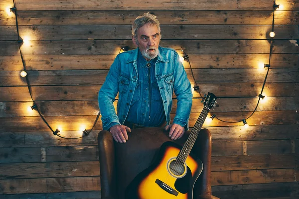 Muzikant met baard leunend op achterzijde stoel — Stockfoto