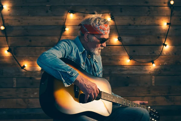 Senior gitarist met baard zit op stoel — Stockfoto