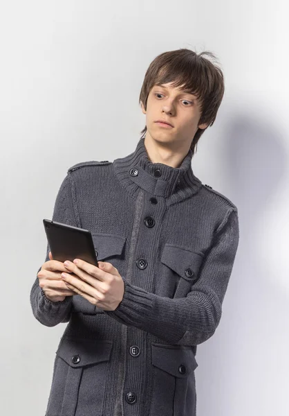Portret fajny młody chłopak stojący w ubranie, trzymając na cyfrowe tabletki stojąc na białym tle — Zdjęcie stockowe