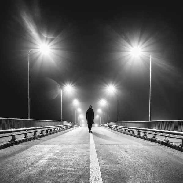 Грустная одинокая женщина, идущая по пустой автостраде ночью — стоковое фото