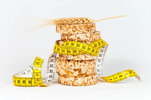 Una cinta métrica amarilla envolviendo una gavilla de tortas de trigo y arroz - concepto de alimentación saludable —  Fotos de Stock