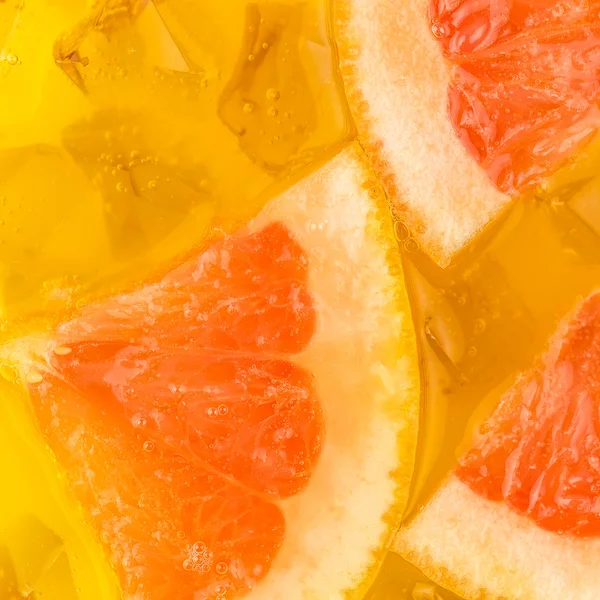 Крупный план кубиков льда в апельсиновом и грейпфрутовом соках — стоковое фото