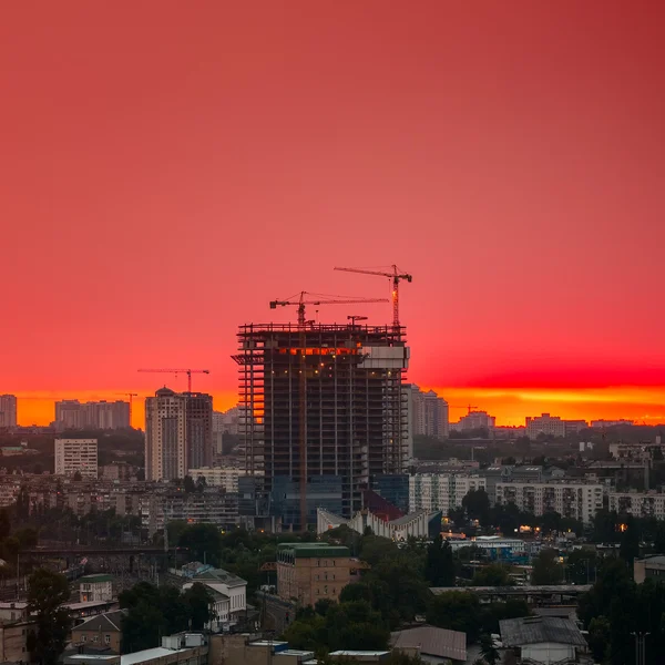 Silueta de la grúa torre en el sitio de construcción con el fondo del edificio de la ciudad — Foto de Stock