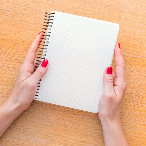 Frau hält Notizbuch auf Holzgrund in der Hand — Stockfoto