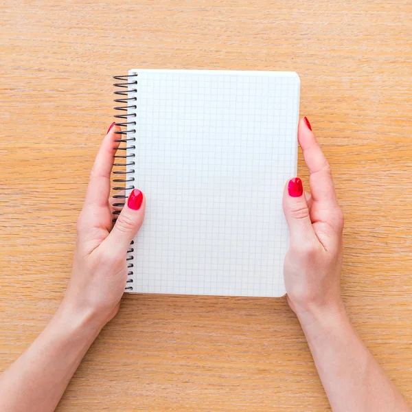 Woman hand holding notebook on wooden background — Stock Photo, Image