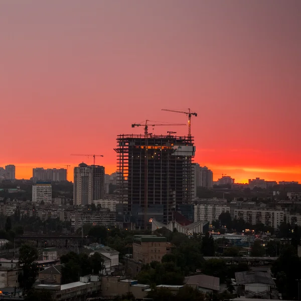 Silueta de la grúa torre en el sitio de construcción con el fondo del edificio de la ciudad — Foto de Stock