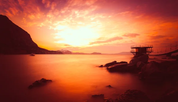 Прекрасний золотий захід сонця над морем і горою — стокове фото