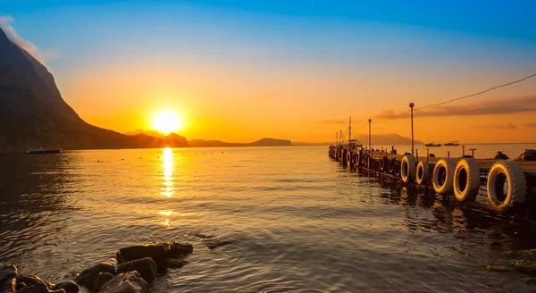 Прекрасний золотий захід сонця над морем і горою — стокове фото