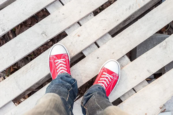 Young man feet in red sneakers on cobbled road — Stock Photo, Image