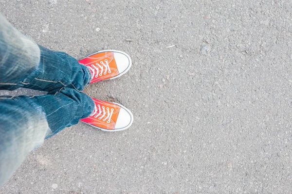 Young man feet in red sneakers on cobbled road — Stock Photo, Image