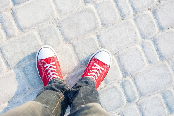 Young man feet in red sneakers on cobbled road — Stock Photo, Image