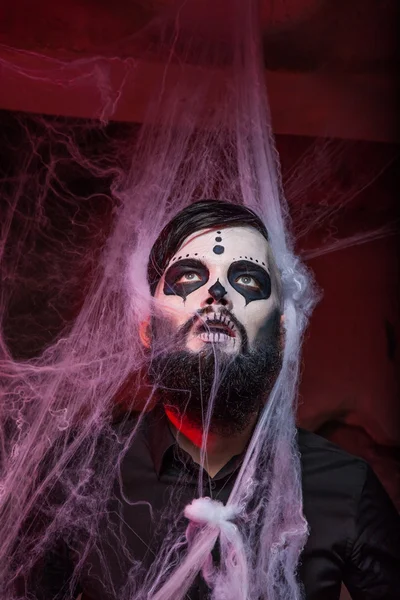 El concepto de Halloween con el hombre joven en el día del arte de la máscara muerta . — Foto de Stock