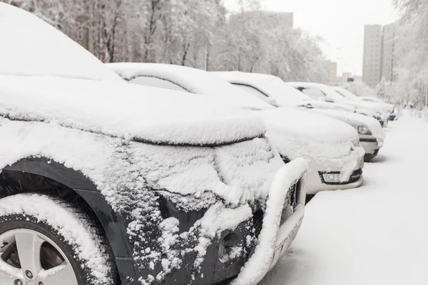 Voertuigen bedekt met sneeuw in de winter sneeuwstorm op de parkeerplaats — Stockfoto