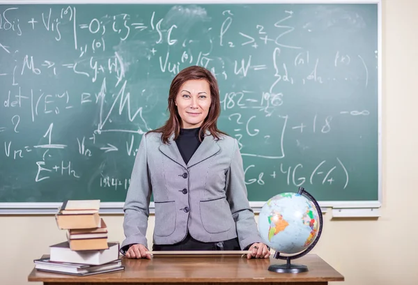 The teacher in the classroom on blackboard background