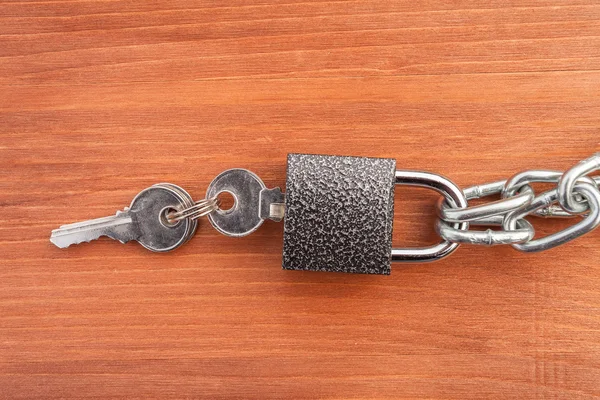 Metal chain links and lock on wooden background — Stockfoto