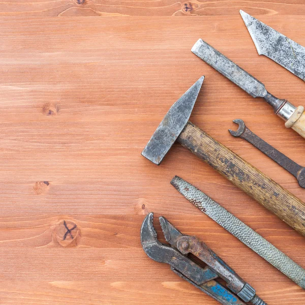 Viejos instrumentos de construcción oxidados sobre el fondo de madera — Foto de Stock