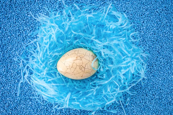 Ραγισμένα Πασχαλινό αυγό στη φωλιά σε μπλε πέτρα φόντο μπλε. — Φωτογραφία Αρχείου