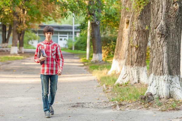 都市の背景に本やタブレットを保持している若い学生男 — ストック写真