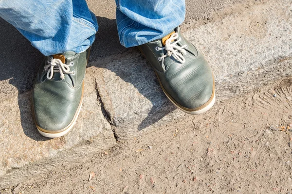Young man feet in sneakers on cobbled road — Stock Photo, Image