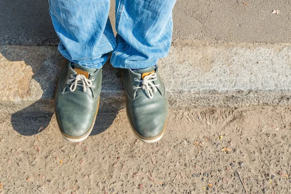 Young man feet in sneakers on cobbled road — Stock Photo, Image