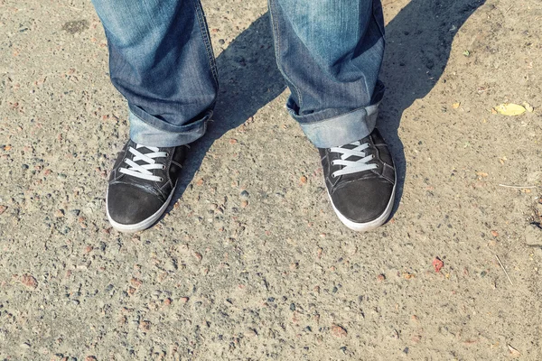 Young man feet in sneakers on cobbled road — Stock Photo, Image