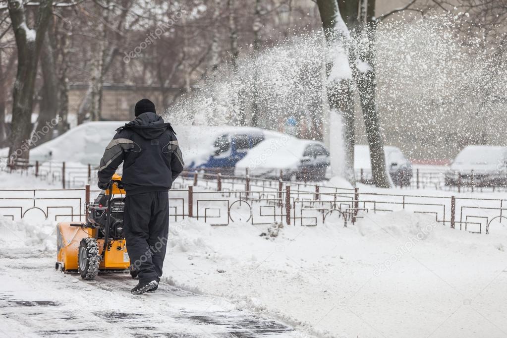 Kiev, Ukraine - January 09, 2016: A man cleans snow from sidewalks with snowblower.