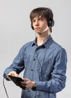 Genç adam onun tablet bilgisayara bağlı kulaklık bir dizi dinlerken onun müzik keyfi