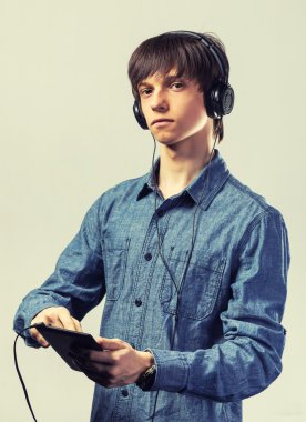 Genç adam onun tablet bilgisayara bağlı kulaklık bir dizi dinlerken onun müzik keyfi. Ton Fotoğraf Filtresi