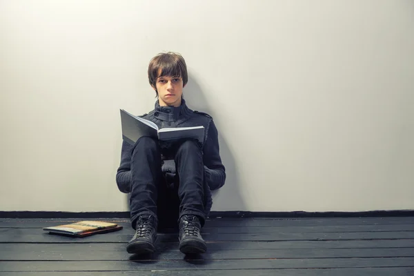 Joven estudiante leyendo libros en piso de madera — Foto de Stock