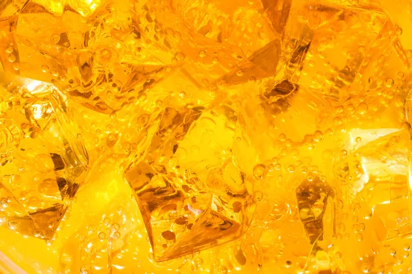 Närbild av isbitar i apelsinjuice — Stockfoto