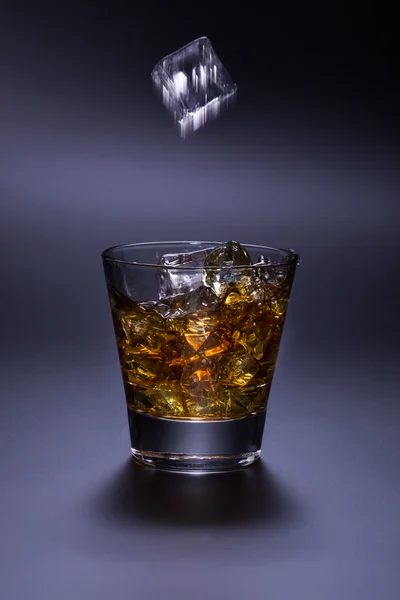 Whiskey with ice in glass on black background — Stock Photo, Image