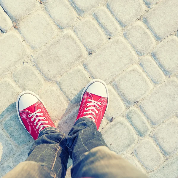 Young man feet in red sneakers on cobbled road — Stock Photo, Image