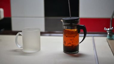 Hot tea is poured into the teapot on the table in the kitchen