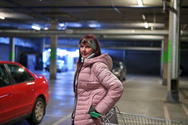 Bir model, bir yeraltı otoparkının arka planına karşı kameranın önünde duruyor. Şehirdeki beyaz bir kadının fotoğrafı..