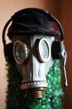 Anti virüs koruma konsepti. Bir gaz maskesinin fotoğrafı, kafasında kulaklık olan bir manken, duvarın arka planında.