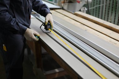 Sanayi konsepti. Bir işçinin fotoğrafı pencere pervazını mezura testeresi kesmek için mezura ile ölçer..