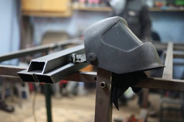 Atölyede metal üzerinde çalışan bir kaynakçının maskesi.