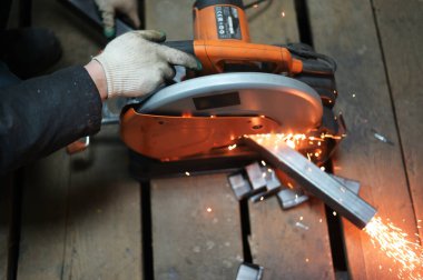 Çalışan bir kaynakçının fotoğrafı atölyedeki bir testereyle metali keser.