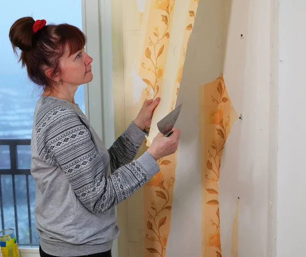 Mujer bonita elimina el papel pintado de la pared en la habitación. Inicio renovación foto. —  Fotos de Stock