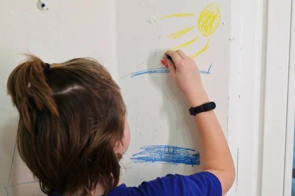 Boy teenager draws on the walls in the room.