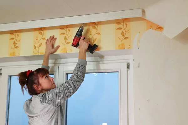 Una donna lavora con un cacciavite in una stanza. Concetto di ristrutturazione casa. Foto Stock Royalty Free