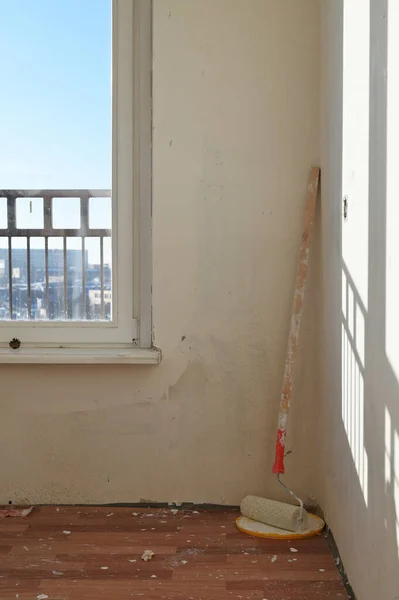 Vertical photo of wall renovation in rooms with paint roller