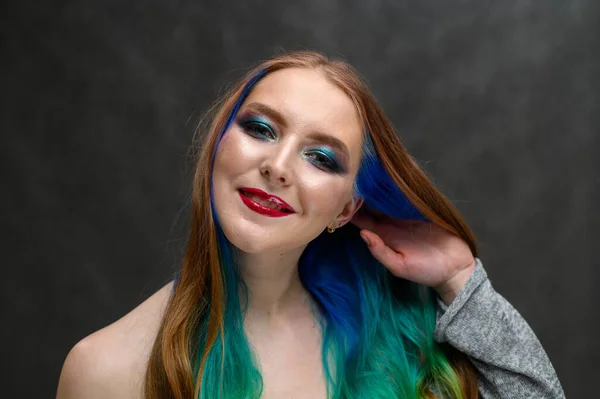 Foto de una mujer feliz. Retrato de una hermosa chica caucásica con el pelo teñido y excelente maquillaje sobre un fondo gris. — Foto de Stock