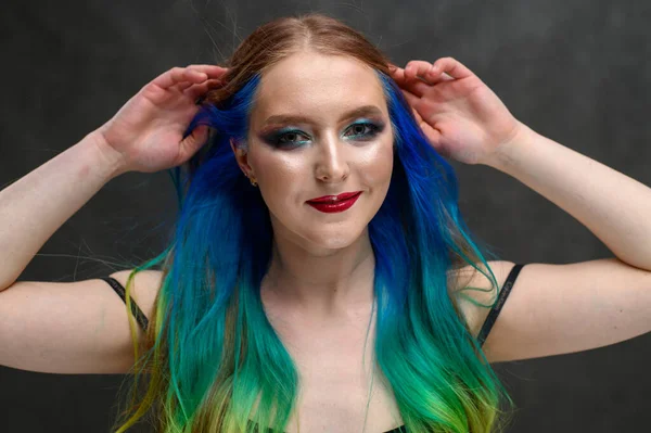 Retrato de uma linda menina caucasiana com cabelo tingido e excelente maquiagem em um fundo cinza. Foto de mulher feliz — Fotografia de Stock